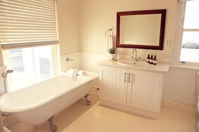a white bathroom with a tub and a sink at Shore's Edge Luxury Oceanfront Home in Hermanus