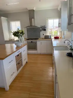 a kitchen with white cabinets and a wooden floor at Shore's Edge Luxury Oceanfront Home in Hermanus