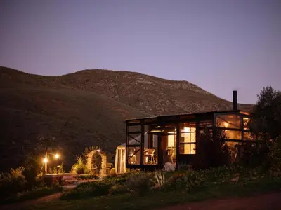 a glass house with a mountain in the background at Southern Yurts in Botrivier