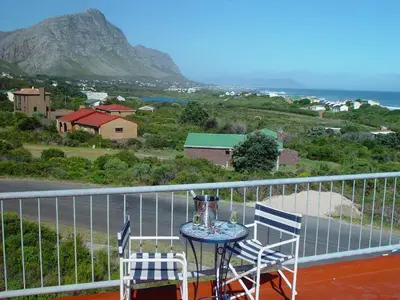 a table and two chairs on a balcony with a view at Jack's Seaview in Bettyʼs Bay