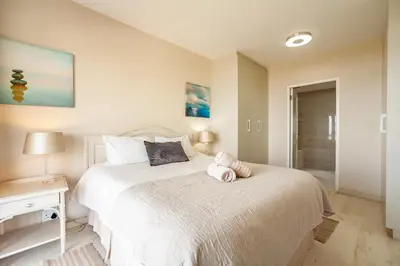 a bedroom with a bed with a pink stuffed animal on it at Luxury Private Beachfront 2 bedroom Dolphin Apartment, Blouberg, Cape Town in Bloubergstrand