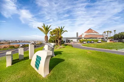 a white fence in the grass next to a road at Luxury Private Beachfront 2 bedroom Dolphin Apartment, Blouberg, Cape Town in Bloubergstrand