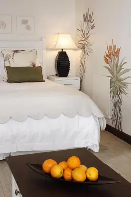 a plate of oranges on a table next to a bed at The Potting Shed Guest House in Hermanus