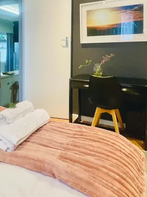 a bedroom with a bed with a desk and a chair at Milnerton Cottage in Cape Town