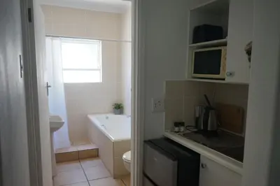 a bathroom with a sink and a toilet and a microwave at Peak Village Lodge in Bloubergstrand