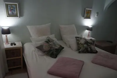 a bed with two pillows on it with two lamps at Peak Village Lodge in Bloubergstrand