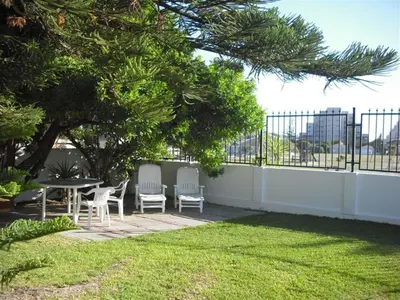 a patio with a table and chairs in a yard at Peak Village Lodge in Bloubergstrand