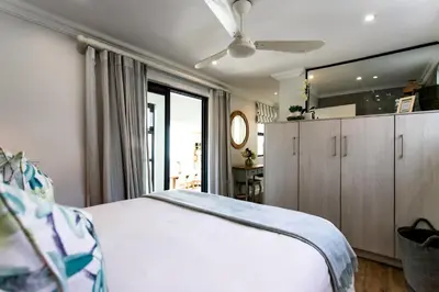 a bedroom with a white bed and a ceiling fan at Serendipity in Hermanus