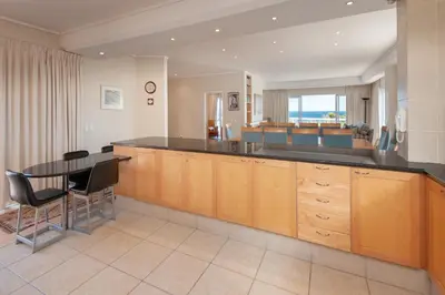 a kitchen with a table and a dining room at Bietou on the Sea in Hermanus