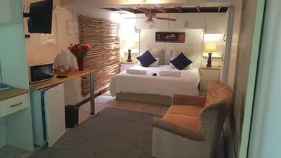 a bedroom with a bed and a couch and a chair at Lodge Strand (The) in Strand