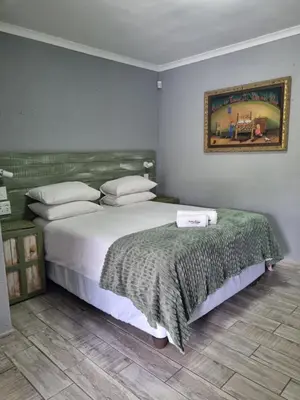 a bedroom with a large bed and a picture on the wall at Northern Vine Guesthouse B&B Self-catering in Brackenfell