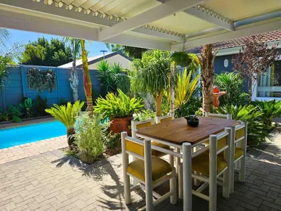 a patio with a table and chairs and a pool at Northern Vine Guesthouse B&B Self-catering in Brackenfell