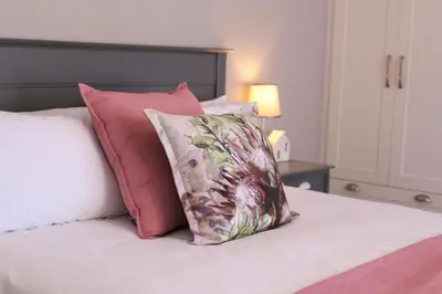 a bed with pink and white pillows on it at Brookshill - Protea suite in Somerset West