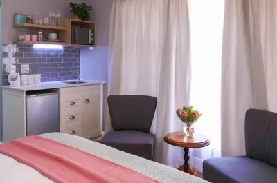 a bedroom with a bed and two chairs and a table at Brookshill - Protea suite in Somerset West