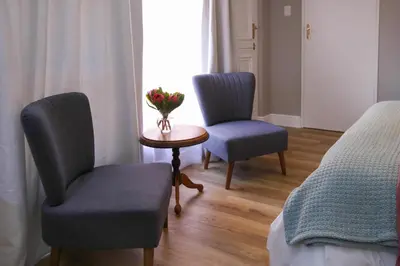 a room with two chairs and a table with flowers on it at Brookshill - Protea suite in Somerset West