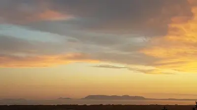 a sunset over a body of water with the sky at Bay View Guest House in Somerset West