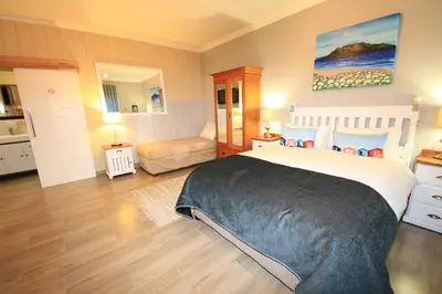 a bedroom with a large bed and a living room at Bay View Guest House in Somerset West