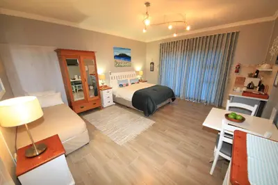 a hotel room with a bed and a table and a desk at Bay View Guest House in Somerset West