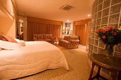 a bedroom with a bed and a living room at Annette Guesthouse in Plattekloof