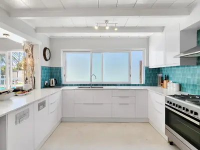 a kitchen with white cabinets and a large window at Salt Boutique Guest House in Bloubergstrand