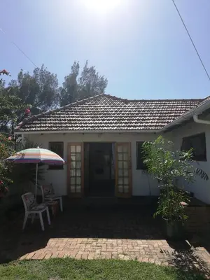 a house with an umbrella and a table and a chair at Coons Cove in Cape Town