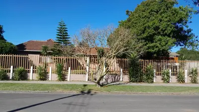 a fence with a tree in front of a house at Coons Cove in Cape Town