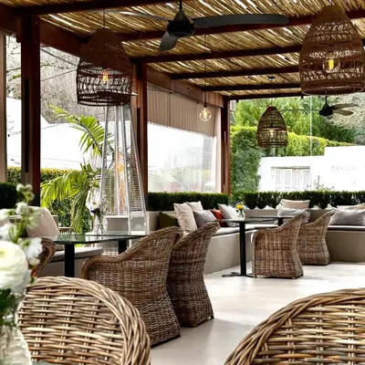 a restaurant with wicker chairs and tables and windows at La Paris Estate in Franschhoek