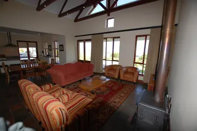 a living room with a red couch and a fireplace at Kingsbury Cottage in Breerivier