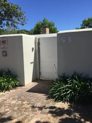 a white fence with a gate with at Just a Bed parking on street in Stellenbosch