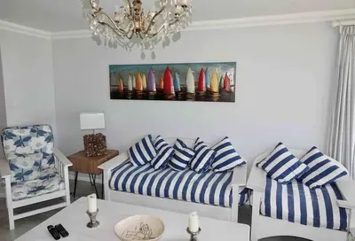 a living room with a couch and surfboards on the wall at Whales & Waves in Hermanus