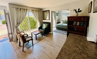 a room with a bedroom with a bed and a chair at D'urban Ridge Self catering Apartment in Cape Town