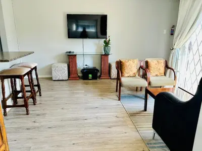 a living room with chairs and a flat screen tv at D'urban Ridge Self catering Apartment in Cape Town