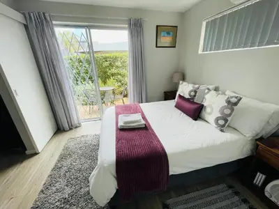 a bedroom with a bed and a window with a table at D'urban Ridge Self catering Apartment in Cape Town
