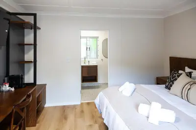 a bedroom with a bed and a desk and a sink at Skinkikofi Guest House in Paarl