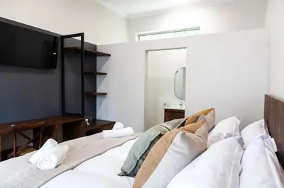 a bedroom with a bed with a tv on the wall at Skinkikofi Guest House in Paarl