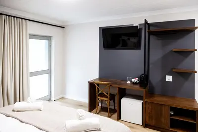 a bedroom with two beds and a desk and a television at Skinkikofi Guest House in Paarl