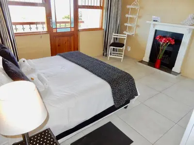 a bedroom with a white bed and a fireplace at Mountain Mist in Bettyʼs Bay