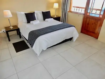 a bedroom with a large bed with white sheets and pillows at Mountain Mist in Bettyʼs Bay