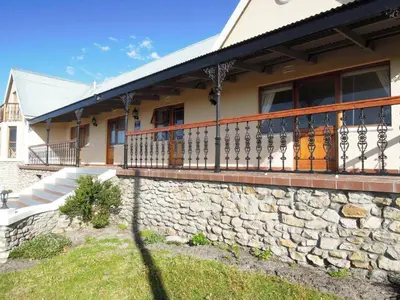 a house with a stone wall and a balcony at Mountain Mist in Bettyʼs Bay