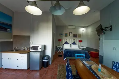 a bedroom with a bed and a kitchen with a sink at @Abelia Guest House in Somerset West