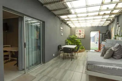 a bedroom with a bed and a dining room with a table at @Abelia Guest House in Somerset West