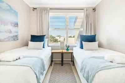 two beds in a room with a window at Marechale Way in Cape Town