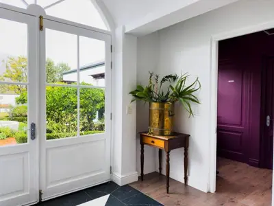 a hallway with a door and a table with a plant on it at Huguenot House in Franschhoek