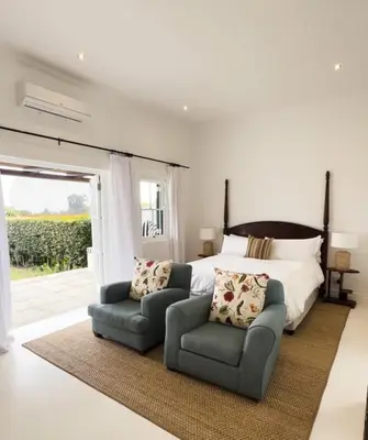 a bedroom with a bed and a pair of chairs at Huguenot House in Franschhoek