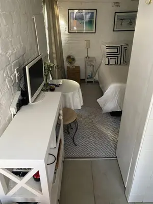 a room with a desk with a computer and a bed at Delightful Surrey Street in Cape Town