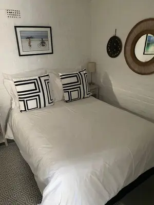 a bed with white sheets and pillows in a bedroom at Delightful Surrey Street in Cape Town