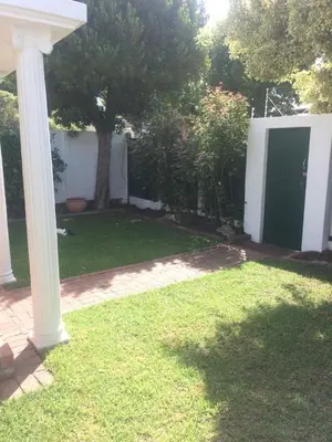 a white house with a green door in a yard at Delightful Surrey Street in Cape Town
