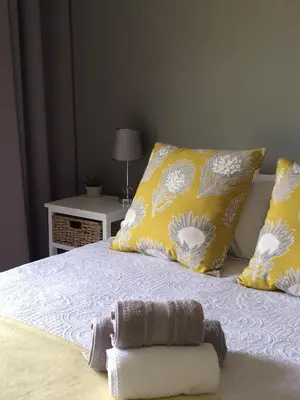 a bed with yellow pillows and a towel on it at Koraalboom Guesthouse in Wolseley