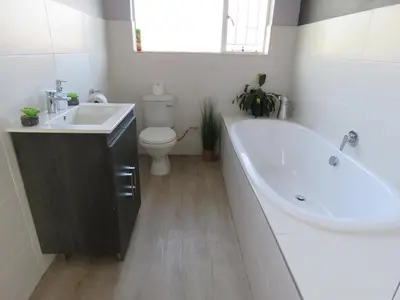 a bathroom with a tub and a toilet and a sink at Koraalboom Guesthouse in Wolseley