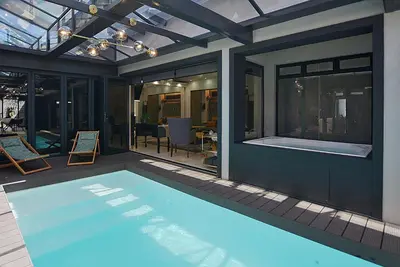 a swimming pool in a house with a patio at Crown Comfort - Affordable luxury - Private Heated Pool & Hot Tub Under Roof in Cape Town
